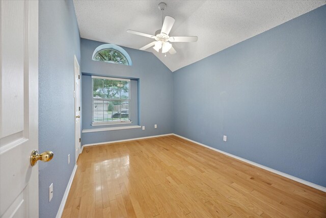 6404 Westgate Dr, North Richland Hills, TX 76182 - empty room with vaulted ceiling, ceiling fan, wood finished floors, and a textured ceiling