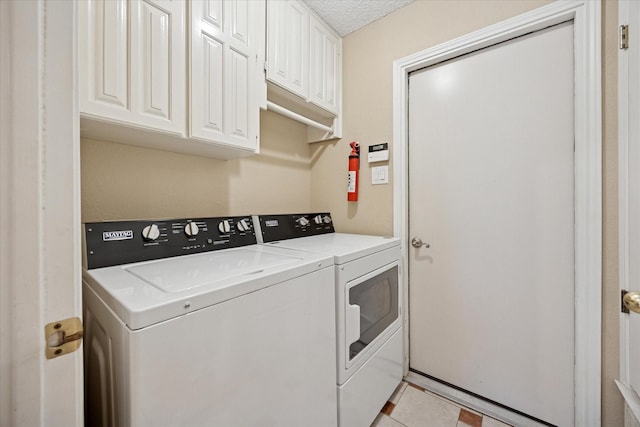 6404 Westgate Dr, North Richland Hills, TX 76182 - laundry area featuring washing machine and clothes dryer, cabinet space, a textured ceiling, and light tile patterned floors