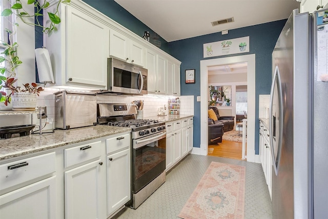 2108 Fairmount Ave, Fort Worth, TX 76110 - kitchen featuring stainless steel appliances, decorative backsplash, white cabinets, and light stone countertops