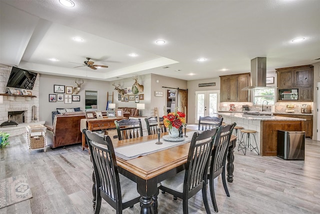 1107 Perkins Rd, Poolville, TX 76487 - dining room with light wood-style flooring, ceiling fan, a fireplace, recessed lighting, and a tray ceiling