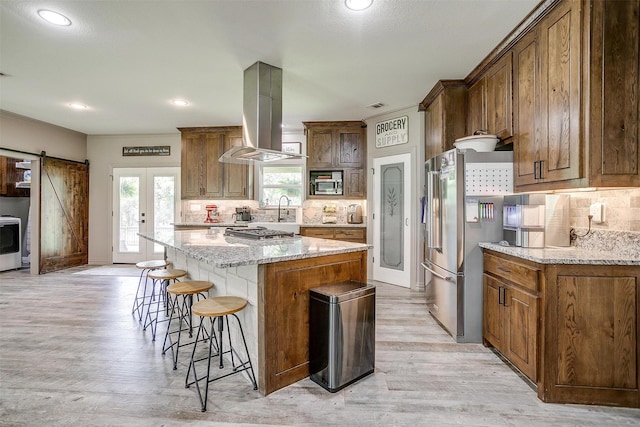 1107 Perkins Rd, Poolville, TX 76487 - kitchen with stainless steel appliances, island exhaust hood, a breakfast bar area, a center island, and tasteful backsplash