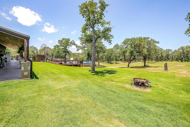 1107 Perkins Rd, Poolville, TX 76487 - view of grassy yard featuring an outdoor fire pit and a wooden deck