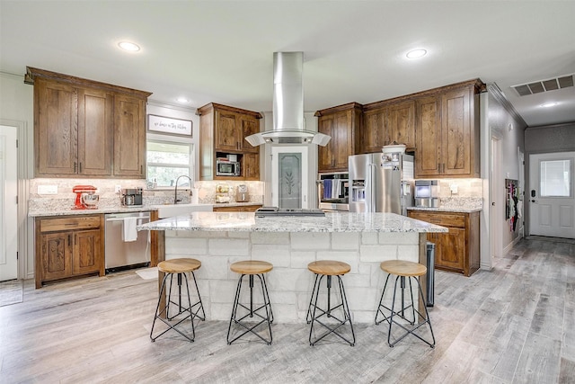 1107 Perkins Rd, Poolville, TX 76487 - kitchen with appliances with stainless steel finishes, island range hood, a kitchen breakfast bar, a center island, and ornamental molding