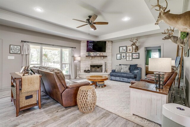 1107 Perkins Rd, Poolville, TX 76487 - living area with a ceiling fan, wood finished floors, a tray ceiling, crown molding, and a stone fireplace