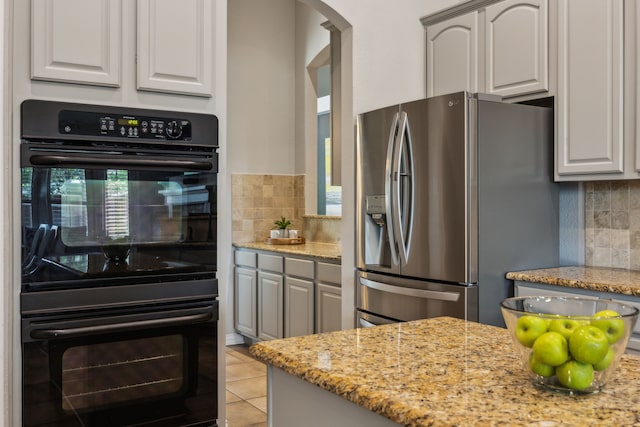 2707 Barnhill Ln, Frisco, TX 75034 - kitchen with stainless steel fridge, arched walkways, decorative backsplash, and light stone counters