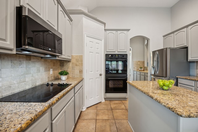 2707 Barnhill Ln, Frisco, TX 75034 - kitchen featuring black appliances, arched walkways, backsplash, light stone countertops, and light tile patterned flooring