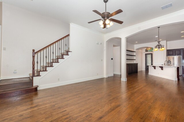 1416 Tangle Ridge Dr, Mckinney, TX 75071 - unfurnished living room with arched walkways, dark wood-style flooring, a ceiling fan, a chandelier, and ornamental molding