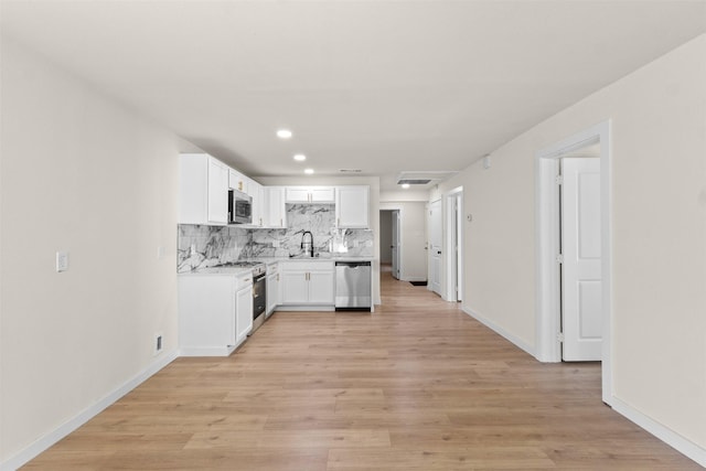 2634 Macon St, Dallas, TX 75215 - kitchen featuring appliances with stainless steel finishes, decorative backsplash, light countertops, white cabinetry, and light wood finished floors