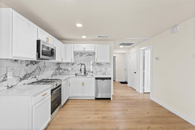 2634 Macon St, Dallas, TX 75215 - kitchen with appliances with stainless steel finishes, backsplash, white cabinets, light countertops, and light wood-style floors