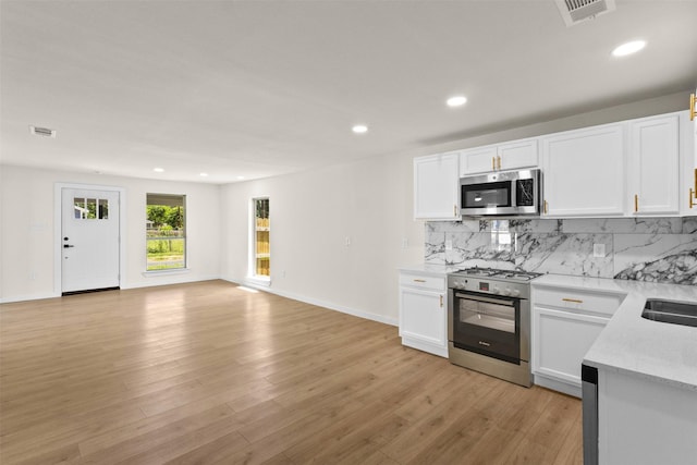2634 Macon St, Dallas, TX 75215 - kitchen with appliances with stainless steel finishes, decorative backsplash, recessed lighting, white cabinetry, and light wood-style floors