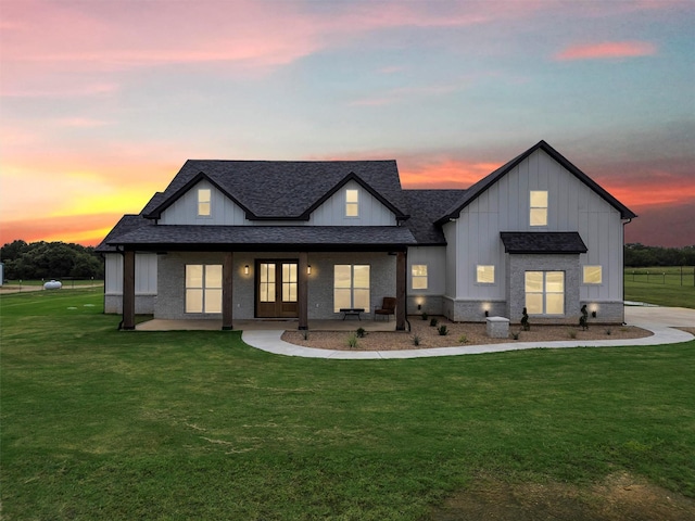 2418 Spirit Ct, Tolar, TX 76476 - back of house at dusk featuring board and batten siding, roof with shingles, a lawn, and french doors