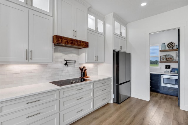 2418 Spirit Ct, Tolar, TX 76476 - kitchen featuring stainless steel appliances, premium range hood, white cabinets, light wood-type flooring, and glass insert cabinets