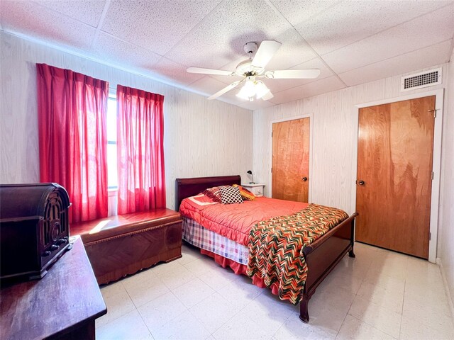 5260 County Road 268, Anson, TX 79501 - bedroom with tile patterned floors, a paneled ceiling, ceiling fan, and wooden walls