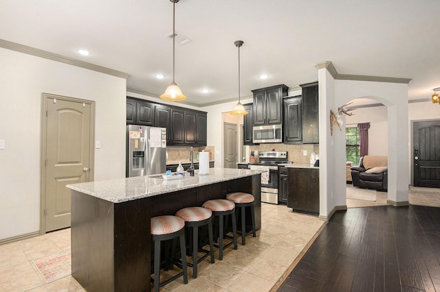 407 Dill Rd, Weatherford, TX 76085 - kitchen featuring stainless steel appliances, ornamental molding, tasteful backsplash, an island with sink, and arched walkways