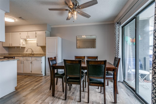 649 Timberline Dr, Hurst, TX 76053 - dining space featuring a textured ceiling, a ceiling fan, light wood-style flooring, and ornamental molding