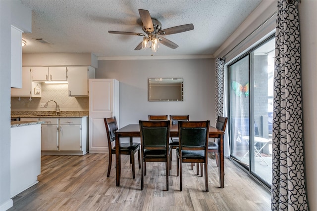 649 Timberline Dr, Hurst, TX 76053 - dining space featuring light wood-type flooring, a ceiling fan, a textured ceiling, and ornamental molding