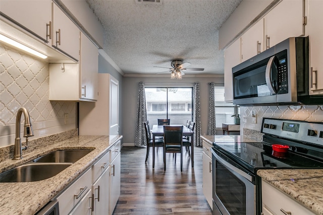 649 Timberline Dr, Hurst, TX 76053 - kitchen featuring stainless steel appliances, a sink, dark wood-style floors, a ceiling fan, and white cabinets