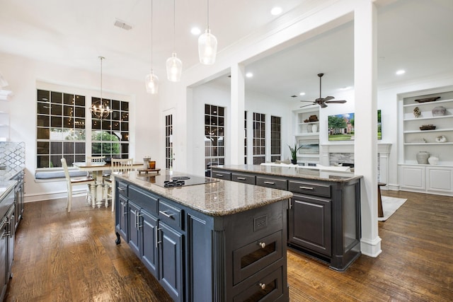 1331 Crockett Dr, Frisco, TX 75033 - kitchen featuring a kitchen island, ceiling fan, black electric cooktop, dark wood-style flooring, and a fireplace