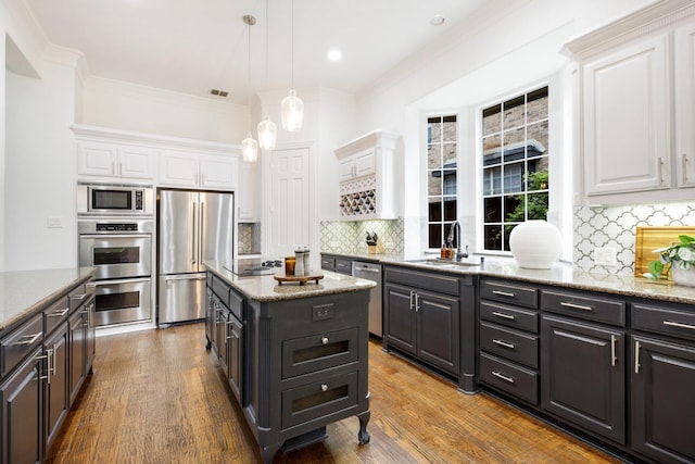 1331 Crockett Dr, Frisco, TX 75033 - kitchen with stainless steel appliances, white cabinetry, a sink, ornamental molding, and tasteful backsplash
