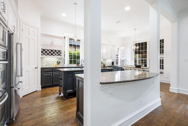 1331 Crockett Dr, Frisco, TX 75033 - kitchen with a kitchen island, dark wood-type flooring, backsplash, dark stone counters, and recessed lighting