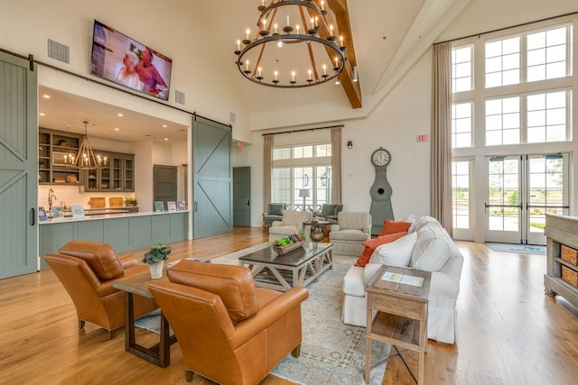 4229 Palomino Rd, Aubrey, TX 76227 - living area featuring a barn door, a chandelier, a towering ceiling, and light wood-style flooring