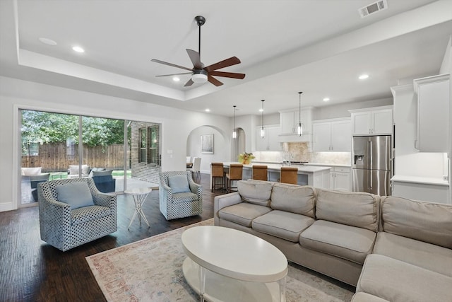 125 Chisholm Trl, Highland Village, TX 75077 - living area with arched walkways, a raised ceiling, dark wood-style floors, baseboards, and a ceiling fan