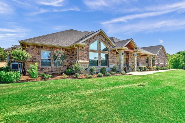 128 Whispering Winds Dr, Gunter, TX 75058 - view of front of property with a shingled roof, a front lawn, central air condition unit, brick siding, and stone siding