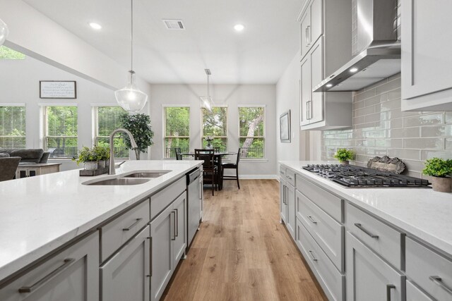 1416 Bearpath Way, Gunter, TX 75058 - kitchen with a sink, wall chimney range hood, stainless steel appliances, decorative backsplash, and light wood-type flooring