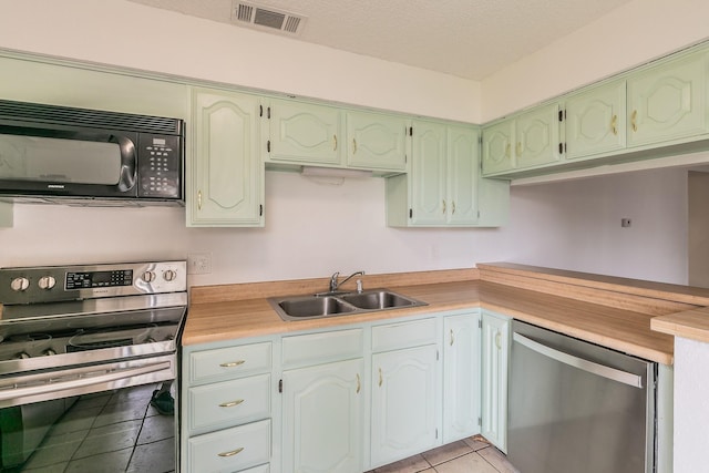 920 Turtle Cv Unit 252, Irving, TX 75060 - kitchen featuring stainless steel appliances, a sink, light tile patterned floors, light countertops, and green cabinets