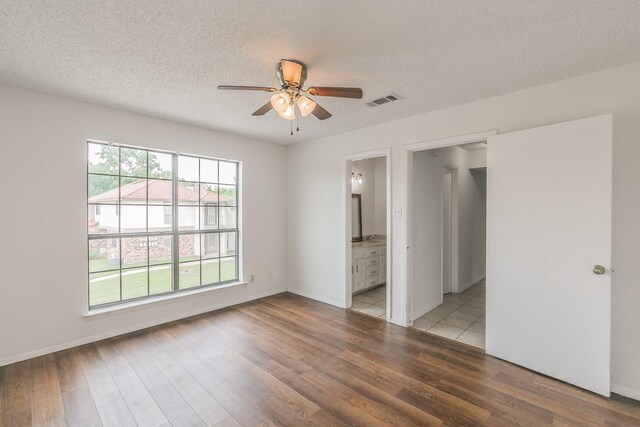 920 Turtle Cv Unit 252, Irving, TX 75060 - unfurnished bedroom with light wood-style floors, a textured ceiling, ensuite bath, baseboards, and a ceiling fan