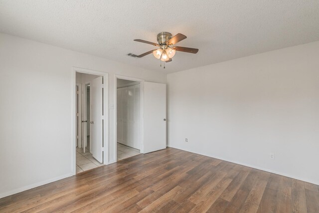 920 Turtle Cv Unit 252, Irving, TX 75060 - unfurnished bedroom featuring wood finished floors, a textured ceiling, ensuite bath, and a ceiling fan
