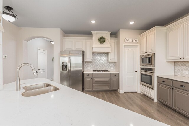 2014 Slow Stream Dr, Royse City, TX 75189 - kitchen with appliances with stainless steel finishes, a sink, wood finished floors, arched walkways, and light countertops