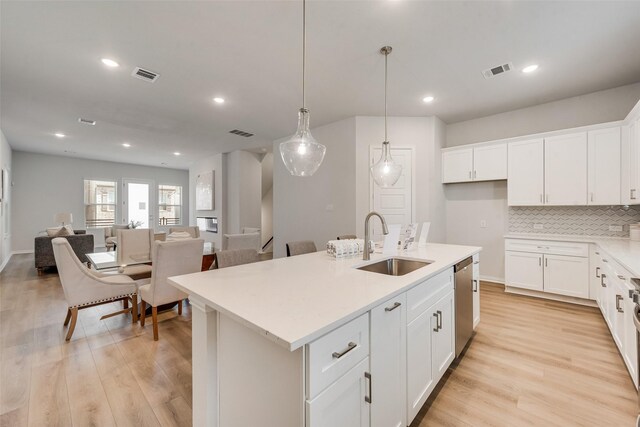 4557 Ward St, North Richland Hills, TX 76180 - kitchen featuring a sink, dishwasher, a center island with sink, light wood finished floors, and backsplash