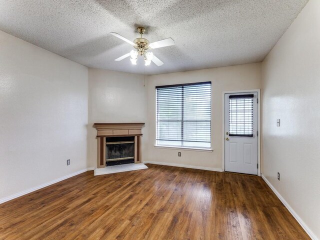 7116 Park Creek Cir E, Fort Worth, TX 76137 - unfurnished living room featuring a textured ceiling, wood finished floors, a ceiling fan, a glass covered fireplace, and baseboards