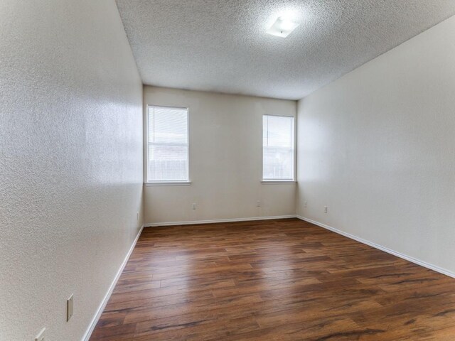 7116 Park Creek Cir E, Fort Worth, TX 76137 - empty room featuring plenty of natural light, a textured ceiling, wood finished floors, a textured wall, and baseboards