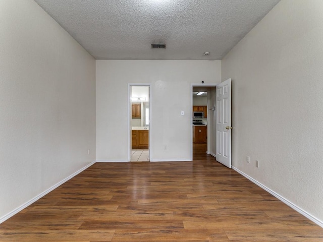 7116 Park Creek Cir E, Fort Worth, TX 76137 - unfurnished bedroom featuring wood finished floors, ensuite bath, a textured ceiling, and baseboards