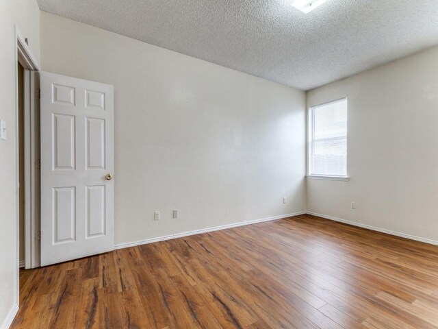 7116 Park Creek Cir E, Fort Worth, TX 76137 - unfurnished room with wood finished floors, a textured ceiling, and baseboards