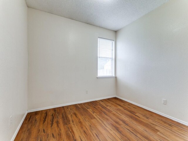 7116 Park Creek Cir E, Fort Worth, TX 76137 - unfurnished room with wood finished floors, baseboards, and a textured ceiling