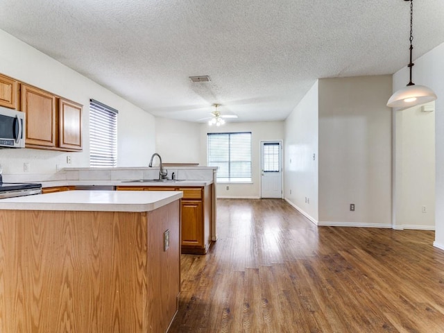 7116 Park Creek Cir E, Fort Worth, TX 76137 - kitchen featuring a sink, stainless steel appliances, light countertops, a ceiling fan, and a peninsula