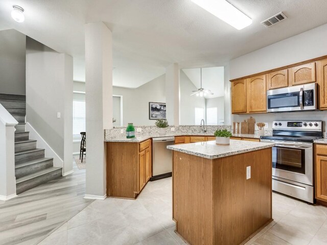 9736 Old Field Dr, Mckinney, TX 75072 - kitchen with appliances with stainless steel finishes, a sink, a kitchen island, light stone counters, and vaulted ceiling