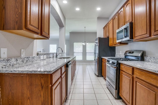 9405 Log Run Ct, Mckinney, TX 75072 - kitchen with stainless steel appliances, a sink, brown cabinetry, light tile patterned floors, and light stone counters