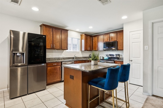2224 Heaton St, Forney, TX 75126 - kitchen with stainless steel appliances, a breakfast bar, a center island, light tile patterned flooring, and dark stone counters