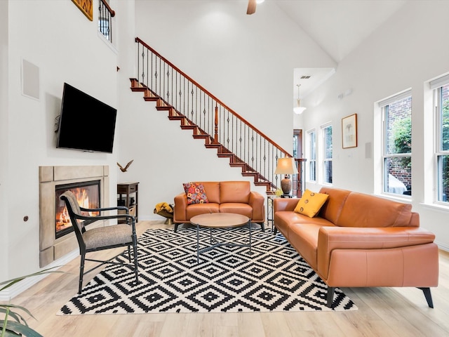 4344 Kestrel Way, Carrollton, TX 75010 - living area with high vaulted ceiling, wood finished floors, a tile fireplace, stairs, and a ceiling fan