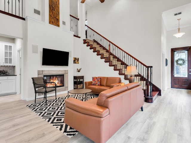 4344 Kestrel Way, Carrollton, TX 75010 - living room featuring a high ceiling, light wood finished floors, a glass covered fireplace, stairway, and a ceiling fan