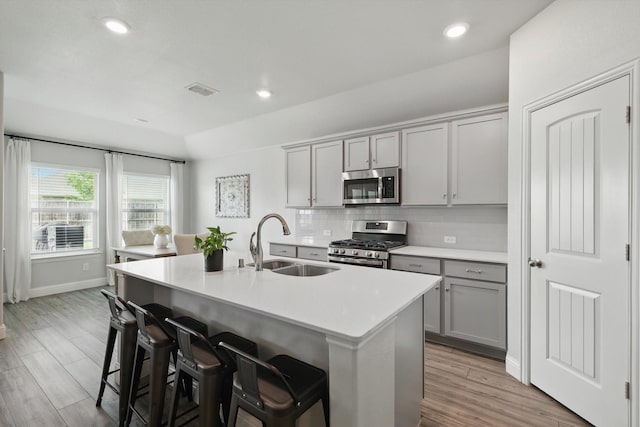 6105 Hightower St, Celina, TX 76227 - kitchen with appliances with stainless steel finishes, a sink, gray cabinetry, backsplash, and an island with sink