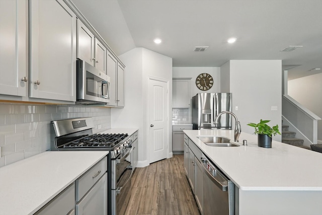 6105 Hightower St, Celina, TX 76227 - kitchen featuring appliances with stainless steel finishes, a sink, gray cabinetry, wood finished floors, and a center island with sink