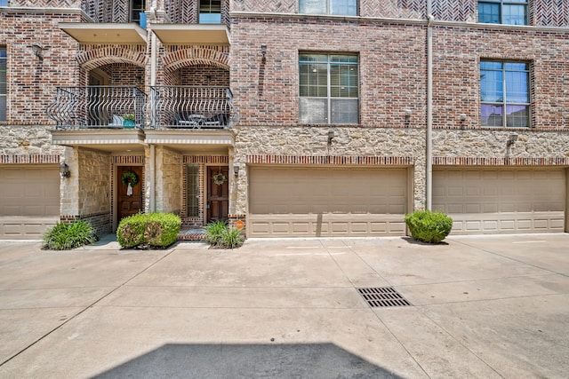 1910 Hope St Unit 15, Dallas, TX 75206 - view of front facade with concrete driveway, a balcony, brick siding, a garage, and stone siding