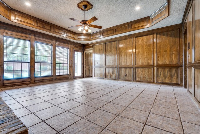1541 Croston Dr, Plano, TX 75075 - empty room with ceiling fan, a textured ceiling, a decorative wall, wood walls, and plenty of natural light