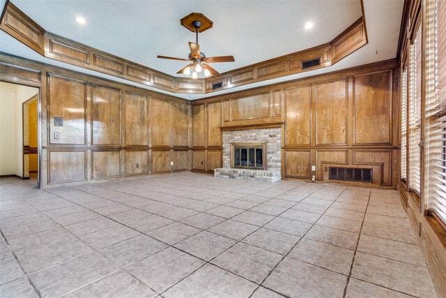 1541 Croston Dr, Plano, TX 75075 - unfurnished living room featuring a fireplace, ceiling fan, a decorative wall, wooden walls, and light tile patterned floors