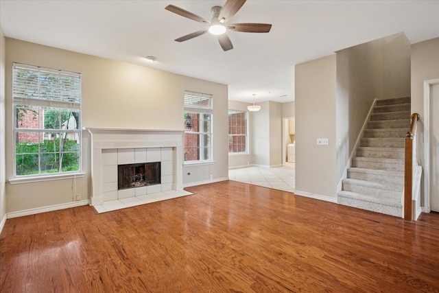 10120 Preston Vineyard Dr, Frisco, TX 75035 - unfurnished living room with a ceiling fan, wood finished floors, baseboards, stairs, and a tiled fireplace